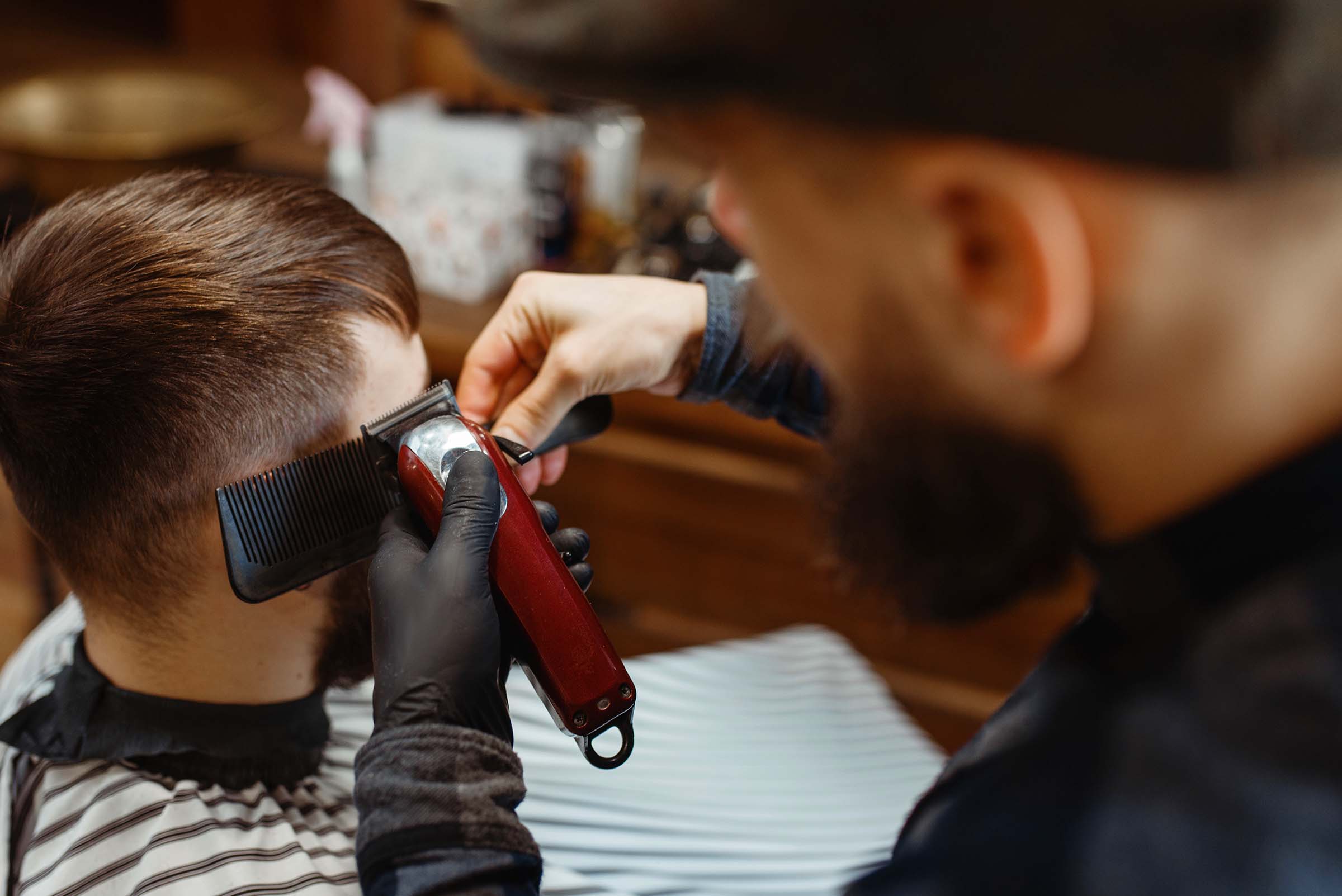 Barber in hat cuts the client 's hair. Professional barbershop is a trendy occupation. Male hairdresser and customer in retro style hair salon