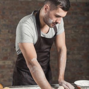 Free Photo _ Male baker rolling dough with rolling pins on kitchen counter